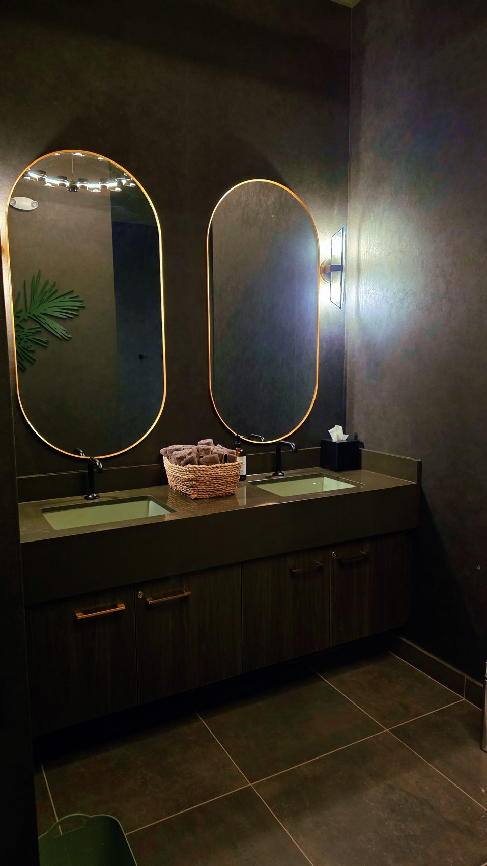 Twin gold oval mirrors over a vanity